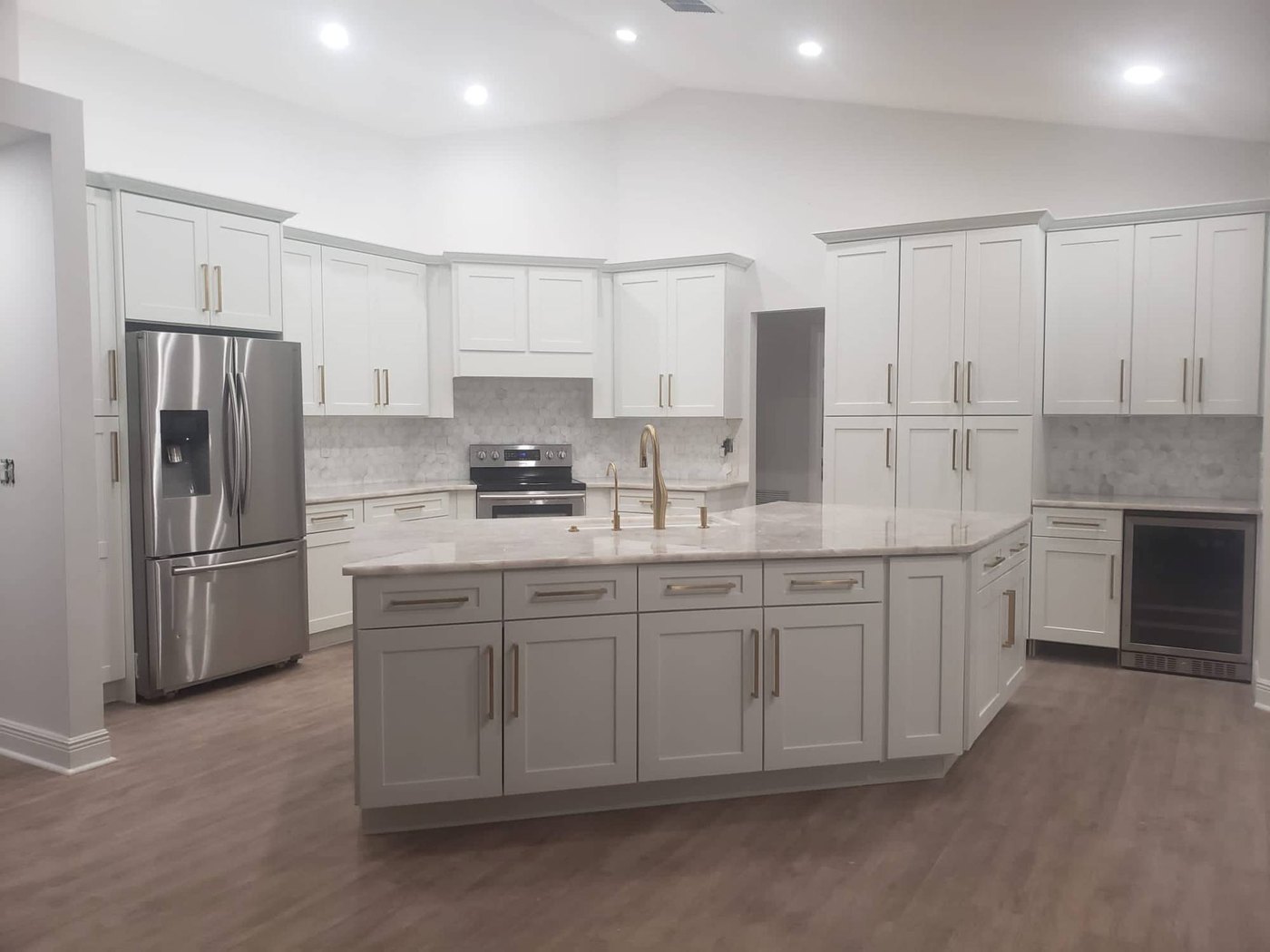 Kitchen remodeled by Rennova Corp: white shaker cabinets, marble countertops, island and brass hardware